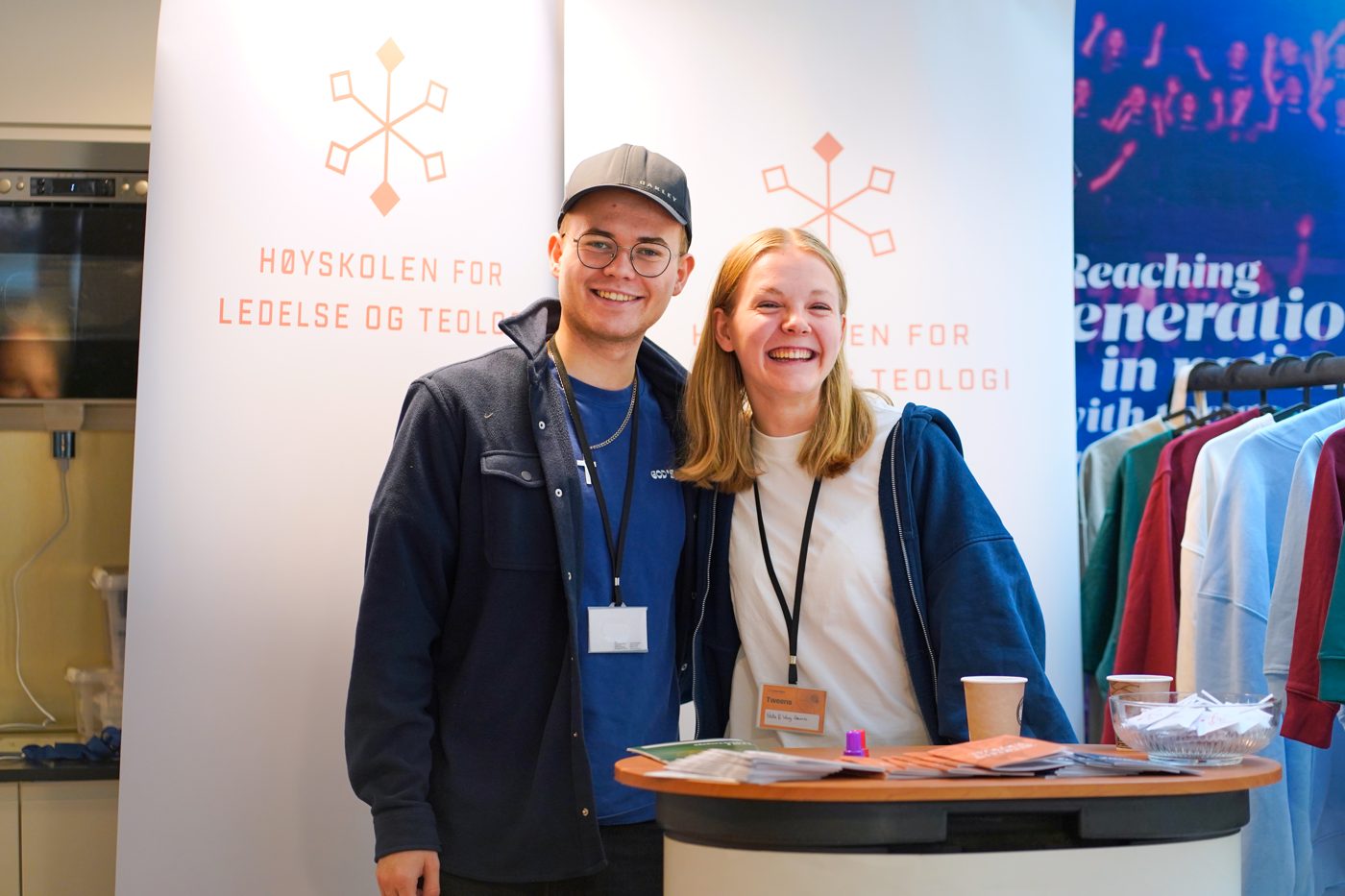 To deltakere ved en stand i foajeen